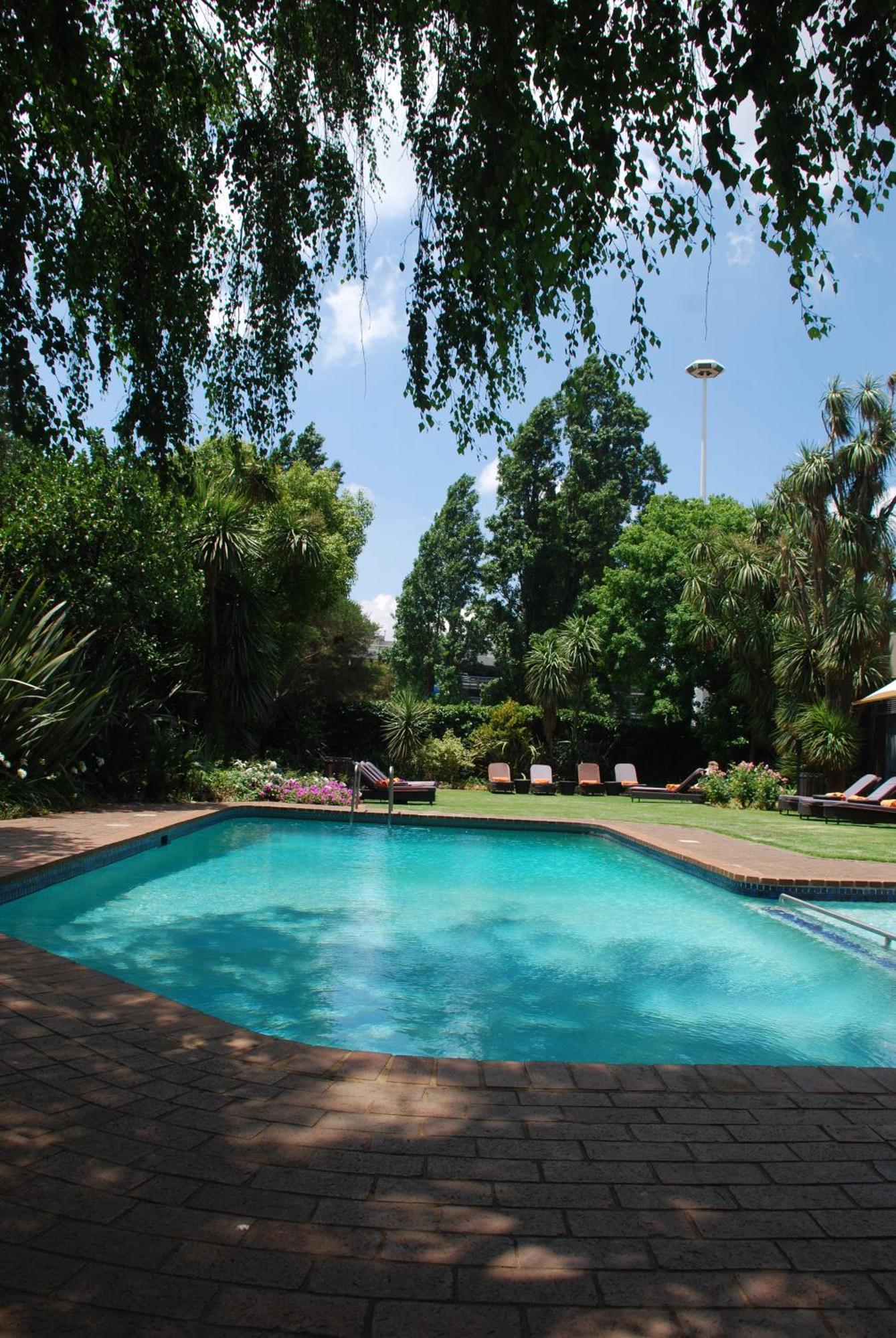 Southern Sun Or Tambo International Airport Kempton Park Exterior photo The garden and swimming pool at the residence